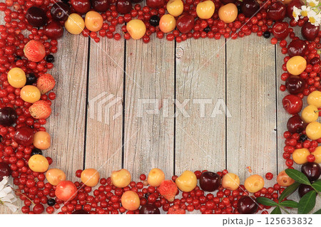Frame of fresh red currant berries, cherries and cherries, top view, copy space. Red currant and sweet cherry on a wooden light background, selective focus, center for text. Frame of fresh red currant berries, cherries and cherries, top view, copy space. Red currant and sweet cherry on a wooden light background, selective focus, center for text. 125633832
