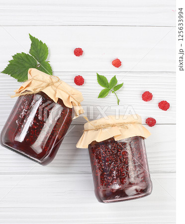 Jars of raspberry jam on a light wooden background with leaves, banner and shop advertisement, healthy natural food concept, home canning concept, Village harvest, breakfast with ingredients, 125633994