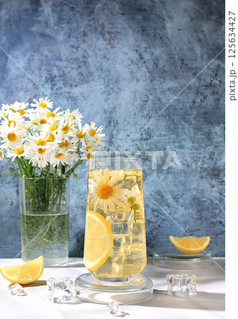 Chamomile tea with lemon in transparent glasses with natural small chamomile flowers on a rustic table, concept of medicinal herbal tea and proper natural nutrition, summer card, 125634427