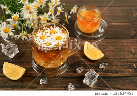 Chamomile tea with lemon in transparent glasses with natural small chamomile flowers on a rustic table, concept of medicinal herbal tea and proper natural nutrition, summer card, Chamomile tea with lemon in transparent glasses with natural small chamomile flowers on a rustic table, concept of medicinal herbal tea and proper natural nutrition, summer card, 125634453