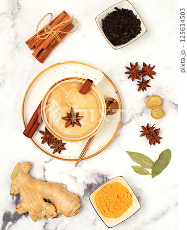 Indian masala chai tea with milk, ginger, anise and cinnamon on an old concrete table. Traditional drink with spices and herbs, cafe concept, restaurant advertising and menu. Selective focus Indian masala chai tea with milk, ginger, anise and cinnamon on an old concrete table. Traditional drink with spices and herbs, cafe concept, restaurant advertising and menu. Selective focus 125634503