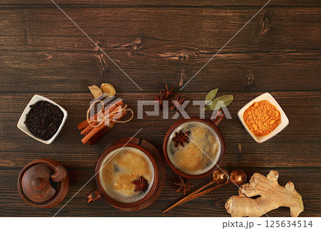 Indian masala chai tea with milk, ginger, anise and cinnamon on an old wooden table. Traditional drink with spices, cafe concept, advertising for restaurant and menu. Selective focus 125634514