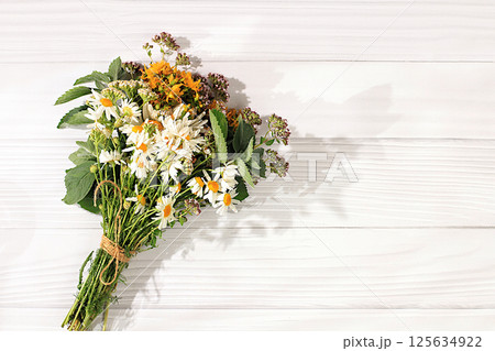 Floral composition of wild medicinal herbs and flowers on a wooden table, Bouquet Hypericum, oregano, fireweed, mint, celandine, chamomile and yarrow, collection of useful herbs for treatment 125634922