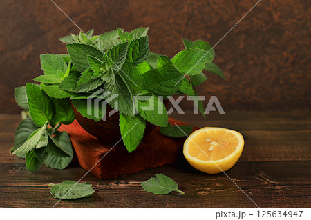 Floral composition of wild medicinal herbs, peppermint in a cup with lemon on a wooden table, collection of useful herbs for treatment according to folk recipes, advertising for a green pharmacy,. Floral composition of wild medicinal herbs, peppermint in a cup with lemon on a wooden table, collection of useful herbs for treatment according to folk recipes, advertising for a green pharmacy,. 125634947