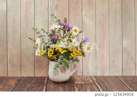 Floral composition of wild herbs and flowers on a wooden table in a rustic style, autumn background, tansy, mint, celandine, chamomile and yarrow in a mug on an old background, collection of useful Floral composition of wild herbs and flowers on a wooden table in a rustic style, autumn background, tansy, mint, celandine, chamomile and yarrow in a mug on an old background, collection of useful 125634958