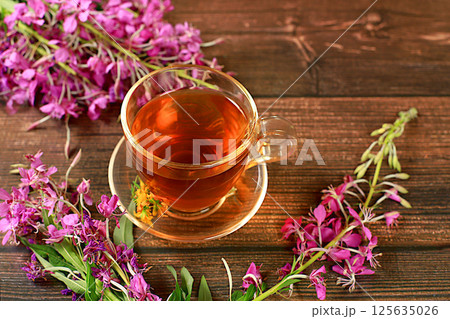 Medicinal herbal tea or fireweed infusion in a glass cup with flowers, the concept of alternative traditional medicine, green pharmacy advertising, collection of useful herbs for treatment according 125635026