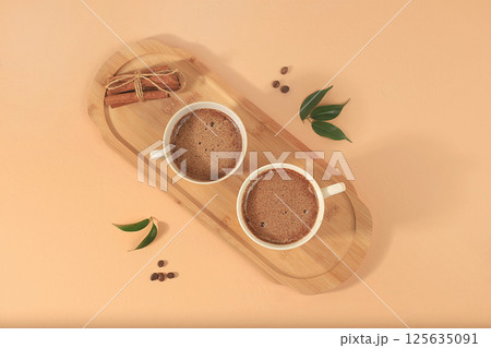 Coffee drink with milk, chocolate and whipped cream, cappuccino coffee, latte, cinnamon, coffee beans on a light table, modern coffee shop advertisement, minimal creative composition, selective focus, 125635091