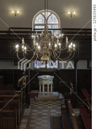 Stunning view of Chandelier hanging from the ceiling over The white octagonal baptismal font inside of The Church of King Charles the Martyr. Stunning view of Chandelier hanging from the ceiling over The white octagonal baptismal font inside of The Church of King Charles the Martyr. 125635493