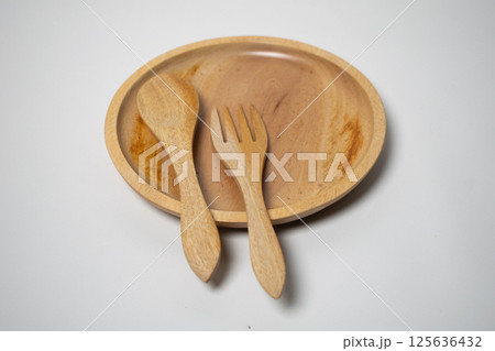 Minimalist wooden tableware set showcasing a spoon, plate, and fork in a flat lay composition. 125636432