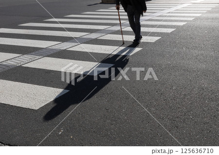 杖をついて大きな交差点横断歩道を渡る年配の男性【シルエット】 125636710