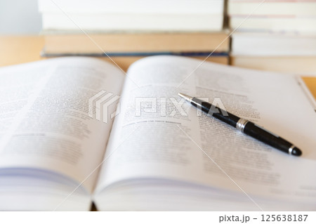 机の上に開いた英語の書籍とペン 研究 学習のイメージ 125638187