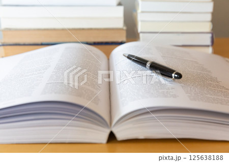机の上に開いた英語の書籍とペン 研究 学習のイメージ 125638188