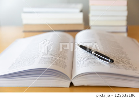机の上に開いた英語の書籍とペン 研究 学習のイメージ 125638190
