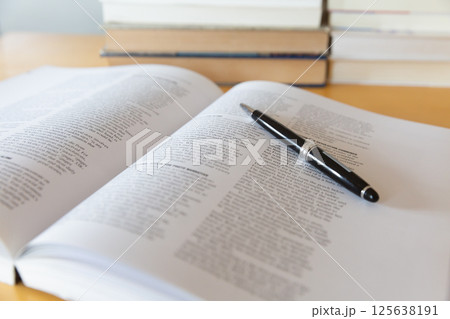机の上に開いた英語の書籍とペン 研究 学習のイメージ 125638191