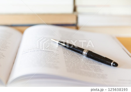 机の上に開いた英語の書籍とペン 研究 学習のイメージ 125638193