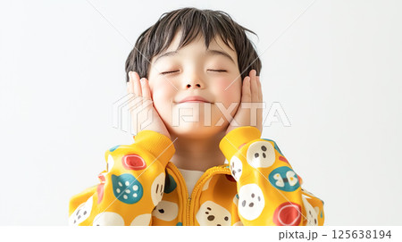 両手を頬に当てて満足そうな表情を浮かべる男の子 両手を頬に当てて満足そうな表情を浮かべる男の子 125638194