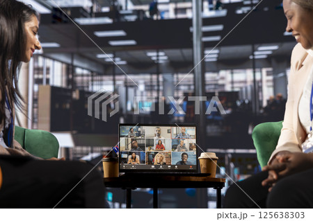 Multicultural team of women leaders hold an online conference call, showcasing collaboration and career growth in a professional, remote setting. Entrepreneurs discuss with investors group. 125638303