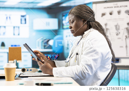 Black physician providing checkup examination on insurance with patient, employing technology for diagnostic tools in clinic. Man asking medic about wellness advice, recovery plan. Black physician providing checkup examination on insurance with patient, employing technology for diagnostic tools in clinic. Man asking medic about wellness advice, recovery plan. 125638316