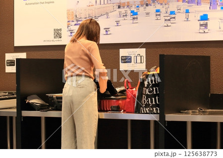 空港の出発ロビーでスーツケースの荷物を詰め替える外国人観光客 125638773