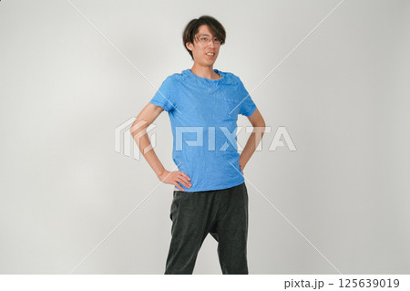 腕を腰にあて、体を少し斜めにしてかっこよく決め、眼鏡をかけてこちらを見つめる男性 125639019