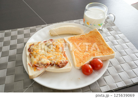 バナナ、ミルクジャムトースト、ミニトマト、牛乳を一度に楽しむバランスの取れた朝食プレート 125639069