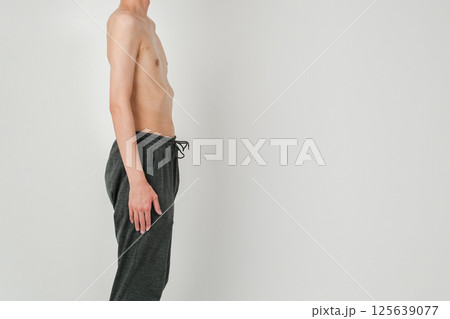 痩せた日本人男性が横を向いて直立の姿勢を取り静かに立っている様子 125639077