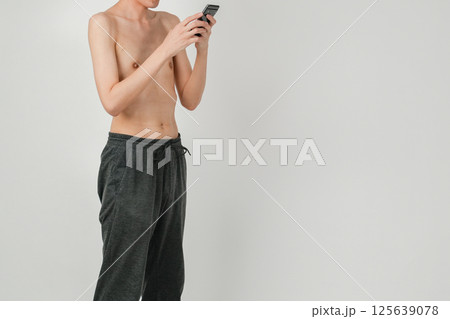 痩せた日本人男性がスマートフォンを操作しているシンプルな日常の一場面 125639078