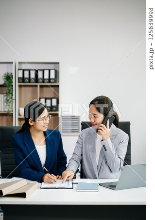 Businesswomen work and discuss their business plans. A women employee explains and shows her colleague in office. 125639998
