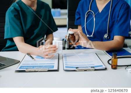 Doctors and nurses collaborate on medical treatment and prescription plans, analyzing data 125640670