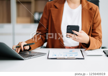 Beautiful Asian business woman typing laptop and tablet Placed at the table Beautiful Asian business woman typing laptop and tablet Placed at the table 125640919