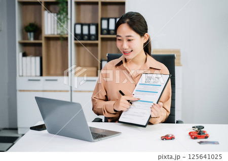 Asian people car salesman or sales manager offers to sell a car and explains of signing a car contract and signing car Asian people car salesman or sales manager offers to sell a car and explains of signing a car contract and signing car 125641025