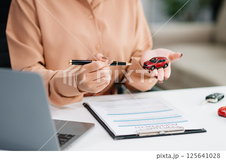 Asian people car salesman or sales manager offers to sell a car and explains of signing a car contract and signing car Asian people car salesman or sales manager offers to sell a car and explains of signing a car contract and signing car 125641028