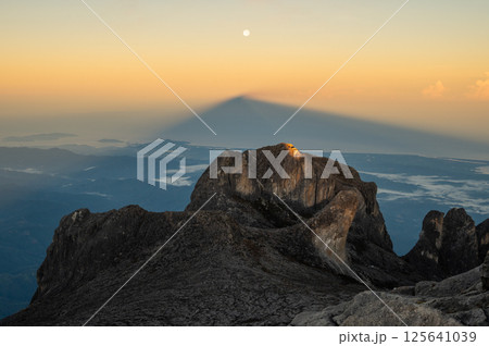 Moonrise over Mt.Kinabalu with the shadow of this mountain during sunrise. Mt Kinabalu is one of the highest mountain in South East Asia. Moonrise over Mt.Kinabalu with the shadow of this mountain during sunrise. Mt Kinabalu is one of the highest mountain in South East Asia. 125641039