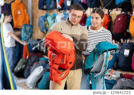 Married couple chooses backpack together for an summer hiking trip in sports store 125641723