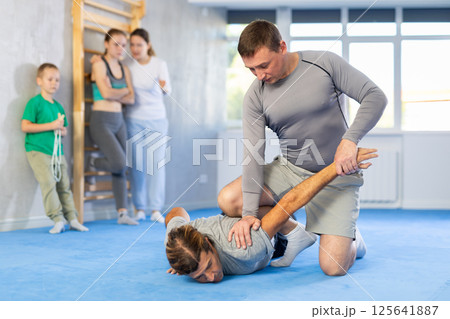 Concentrated man with trainer in sport club during self-defense training, sparring and practicing technique of hand grab Concentrated man with trainer in sport club during self-defense training, sparring and practicing technique of hand grab 125641887