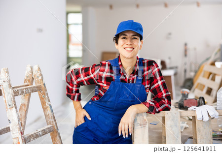 Young woman builder in work clothes posing in apartment during repair works 125641911