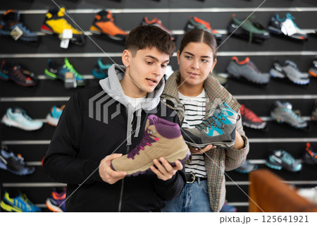 Married couple choose winter trekking shoes together in sports shop Married couple choose winter trekking shoes together in sports shop 125641921