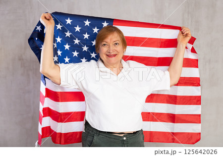 Cheerful senior woman holding national flag of United States 125642026