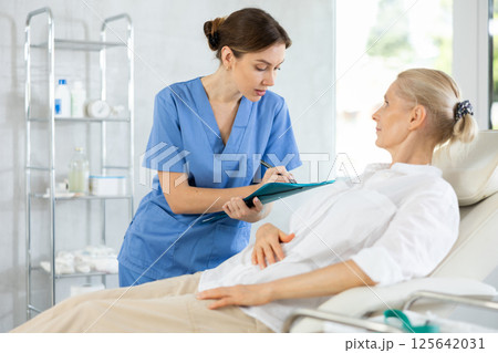 Woman doctor conducting questionnaire of elderly female patient in medical office Woman doctor conducting questionnaire of elderly female patient in medical office 125642031