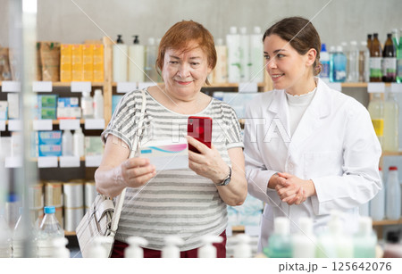 Woman buyer scans pills qr code with woman pharmacist 125642076