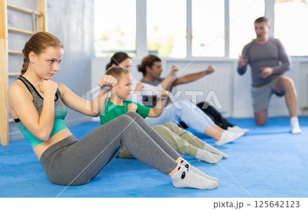 Group of people performing combat strikes sitting during group training Group of people performing combat strikes sitting during group training 125642123