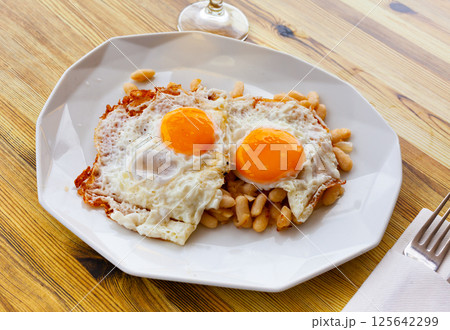 Fried eggs with stewed white beans for breakfast 125642299