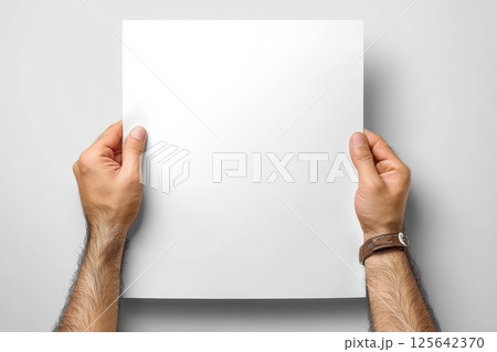 Hands Presenting a Blank Mockup Paper in Front of a Simple Gray Background 125642370