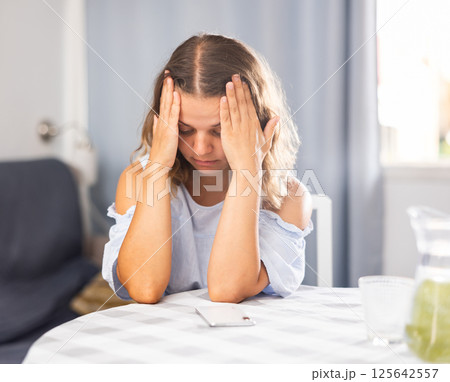 Sad single woman sitting in living room Sad single woman sitting in living room 125642557