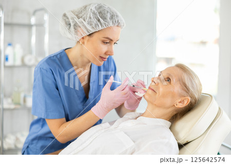 Elderly woman undergoing lips lifting procedure in cosmetology clinic 125642574