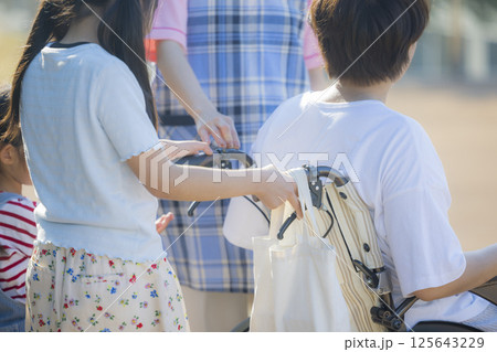 車椅子を押す小学生と介護士　ヤングケアラー 　 125643229