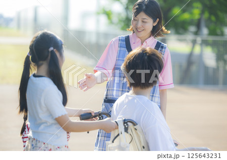 車椅子を押す小学生と介護士　ヤングケアラー 　 125643231