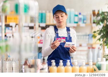 In sales area of pharmacy, builder woman examines packaging of paracetamol pill 125643309