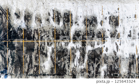 Aerial view from above a snow covered parking lot with the lines covered in some locations. 125643324