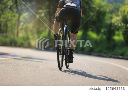Woman cyclist riding bike at summer park Woman cyclist riding bike at summer park 125643338
